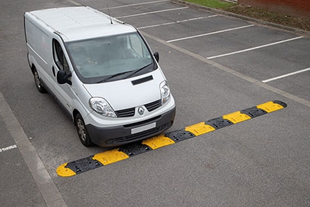 Large white van drives over a black and yellow Seton Speed Bump in a car park